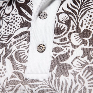 Close-up of a white piqué cotton polo shirt with tropical plant prints and two buttons