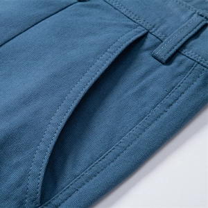 Close-up of high-density cotton twill fabric and stitching on blue men's casual shorts