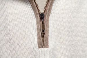 Detail view of half-zip collar with metal zipper on men's white knit sweater