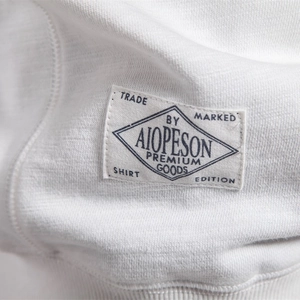 Close-up of premium white cotton crewneck sweatshirt with AIOPESON brand label detail