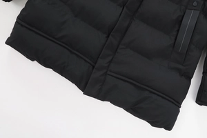 Dettaglio dell'orlo trapuntato e della tasca laterale di un parka nero uomo con cappuccio