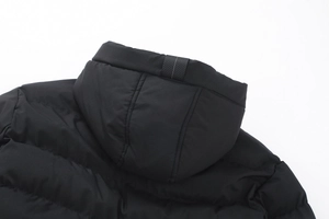 Dettaglio del cappotto invernale nero con cappuccio, cuciture orizzontali e nastro tessuto