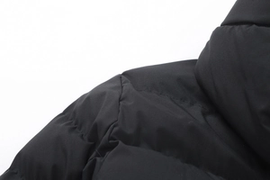 Dettaglio ravvicinato del parka nero con tessuto opaco e cuciture trapuntate di qualità