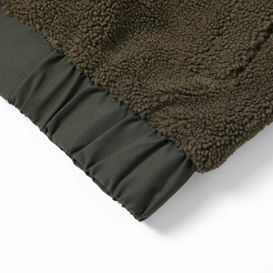 Detail der Teddy-Fleecejacke mit braunem Sherpa-Stoff und grüner Rippbündchen-Struktur