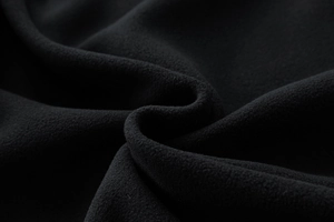 Macro del tessuto in pile polare nero che mostra la consistenza morbida e calda