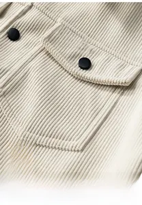 Detail of beige corduroy jacket showing breast pocket with black button and ribbed texture