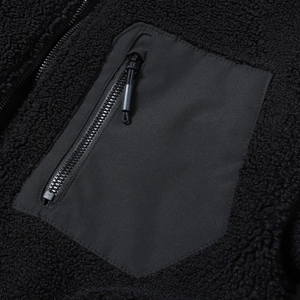 Detailansicht der schwarzen Teddy-Fleecejacke mit gewebter Brusttasche und Reißverschluss