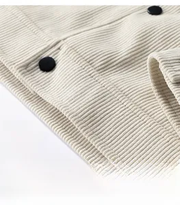 Close-up of beige corduroy jacket hem with black buttons and neat stitching detail