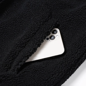 Detailansicht der tiefen Seitentasche einer schwarzen Teddy-Fleecejacke mit Smartphone
