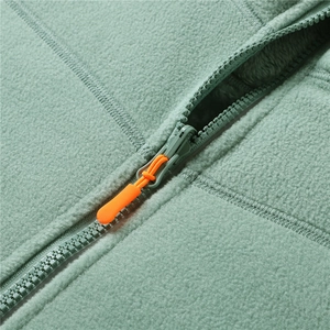 Detail of pea green polar fleece fabric with zipper and bright orange decorative pull cord