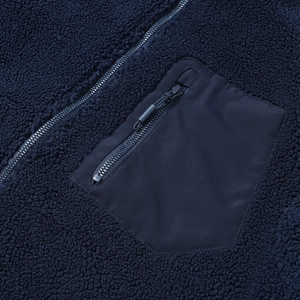 Detail der marineblauen Teddyfleece-Jacke mit gewebter Brusttasche und Metallreißverschluss