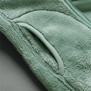 Macro detail of mint green fleece jacket showing pocket construction and soft texture