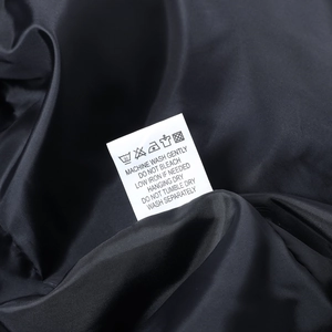 Detailaufnahme des Waschetiketts auf schwarzem Futter mit Pflegehinweisen für Kleidung