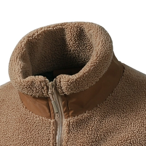 Makroaufnahme des braunen Teddy-Fleece-Jackenkragens mit Stehkragen und Metall-Reißverschluss
