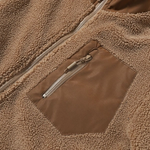 Detailaufnahme des Reißverschlusses und der Brusttasche an der braunen Fleecejacke