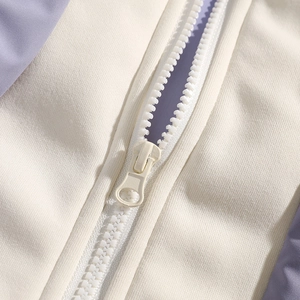Detail of high-quality zipper and patchwork fabric on a beige and purple puffer jacket
