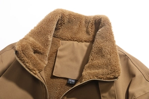 Dettaglio macro del colletto della giacca kaki con fodera in pile e zip in metallo oro