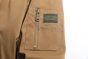 Dettaglio giacca in twill kaki con tasca con zip in metallo ed etichetta in tessuto