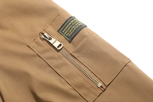 Dettaglio della giacca bomber kaki con tasca con cerniera in metallo e etichetta fashion