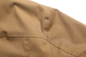 Vista macro dettagliata della giacca outdoor kaki con doppie cuciture rinforzate in twill di cotone