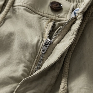Detailed close-up of khaki cargo pants featuring high-quality metal zipper and drawstrings
