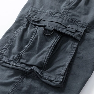Detailed close-up of dark grey cargo pants featuring a large flap pocket and black D-ring