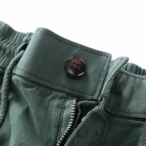 Detail of olive green cargo pants featuring an elastic drawstring waist and metal zipper