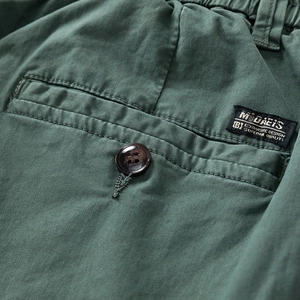 Detailed macro view of dark green cargo pants rear pocket with button and textile label