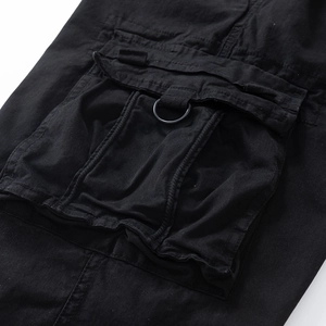 Detail of durable black cargo pants showing 3D flap pocket and metallic D-ring feature