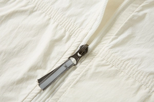 Close-up of white UPF 100+ sun shirt showing fabric texture and reflective zipper pull