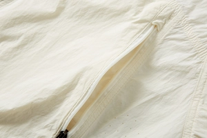 Detailed close-up of cream sun-protective jacket showing laser-cut breathability holes