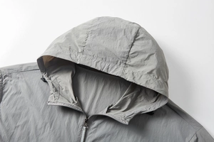 Detailed macro view of gray sun protection jacket showing hood texture and metal zipper