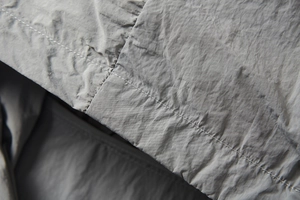 Macro detail of silver-grey UPF100+ fabric with precise double-row stitching and texture
