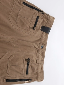 Detail of khaki cargo pants showing waist button, zipper pockets and durable cotton fabric