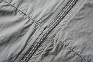 Detailed macro view of gray UPF100+ sun protection jacket zipper and double stitching