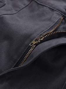 Close-up of bronze metal zipper on charcoal grey heavy cotton cargo pants fabric