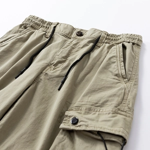 Detail of khaki cargo pants showing elastic drawstring waist and tactical button pockets