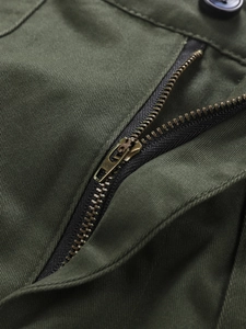 Detail of vintage bronze metal zipper and olive green cotton twill fabric on cargo pants