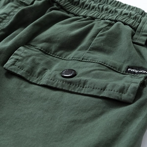 Detail view of dark green cargo pants featuring elastic waist and fashion woven label
