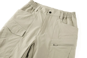 Detail of khaki tactical pants featuring reinforced stitching and utility zipper pockets