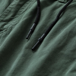 Detail of dark green cargo pants featuring black drawstring cords and neat stitching