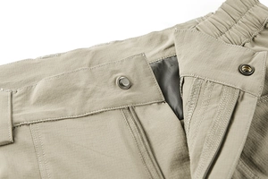 Detail of khaki tactical pants featuring elastic waist, snap button, and durable ripstop fabric