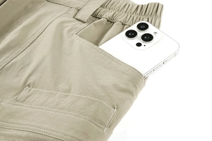 Macro detail of khaki tactical pants showing deep side pockets with a smartphone inside