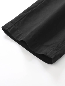 Detailed macro view of black twill cotton cargo pants showing precise stitching and hem line