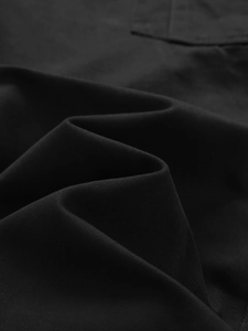 Detail of black twill fabric on outdoor cargo pants with reinforced stitching details