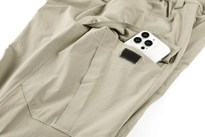 Detail view of khaki tactical pants featuring a large cargo pocket with a phone for size