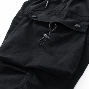 Detailed close-up of cargo pants utility pocket with snap buttons and drawstring cord