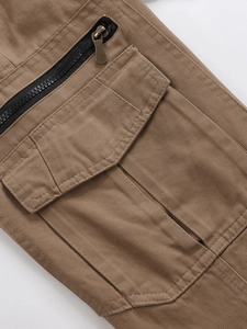 Detail of khaki cargo pants featuring a large flap pocket and black zipper closure detail