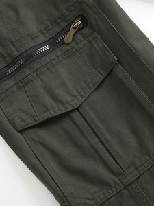 Macro detail of military green cotton cargo pants with metal zipper and flap pocket
