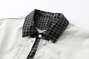 Detail of plaid collar lining and metallic snap buttons on casual beige jacket